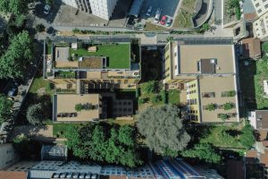 Vue aérienne du jardin de la résidence 25 place Croix-Rousse avec des plantations, des toits végétalisés, des bacs acier, des jardinières, un terrain de pétanque et des arbres