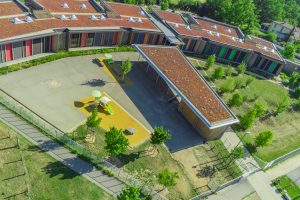 Une cour d'école végétale avec des cheminements, des prairies fleuries, des jeux et des arbres